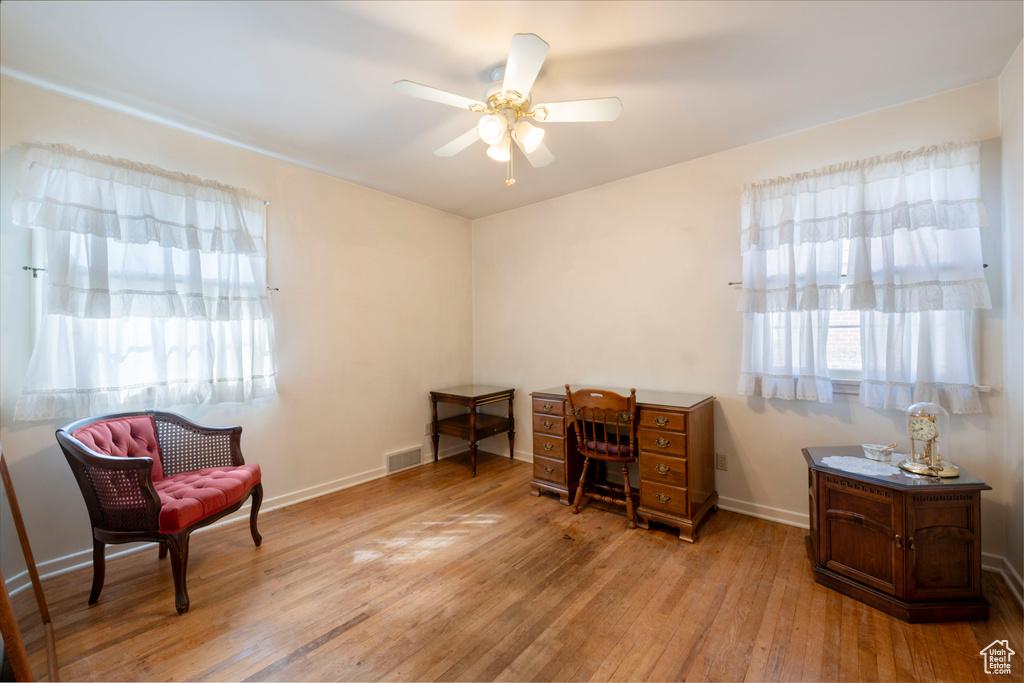 Office area with hardwood / wood-style floors, visible vents, baseboards, and ceiling fan