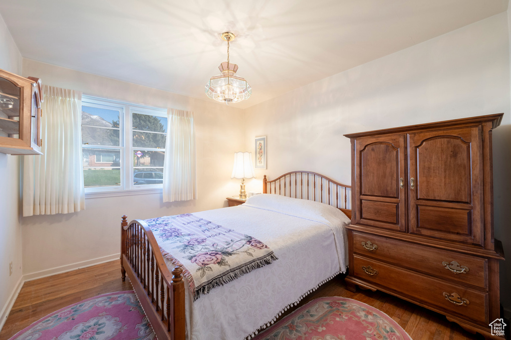 Bedroom featuring baseboards, dark wood-style floors, and a chandelier