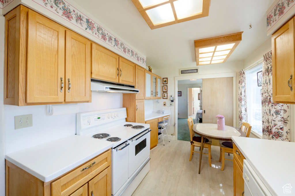 Kitchen with light countertops, light wood finished floors, white appliances, under cabinet range hood, and light brown cabinetry