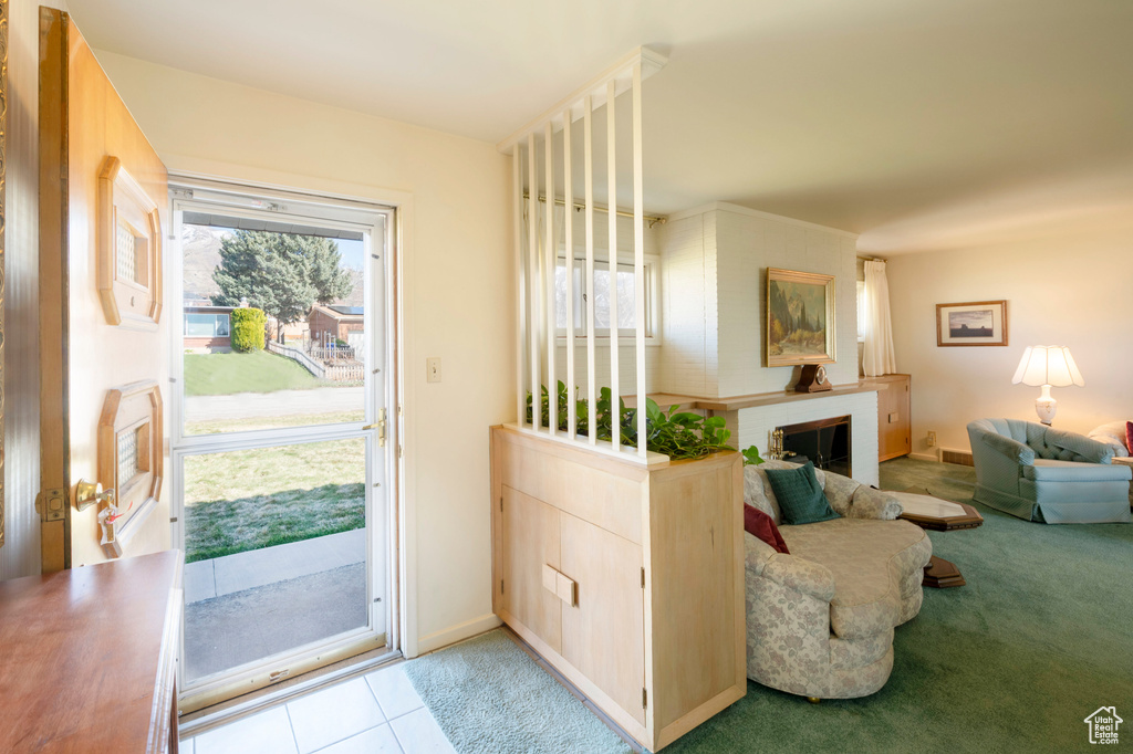 Doorway to outside featuring baseboards, carpet flooring, tile patterned floors, and a brick fireplace