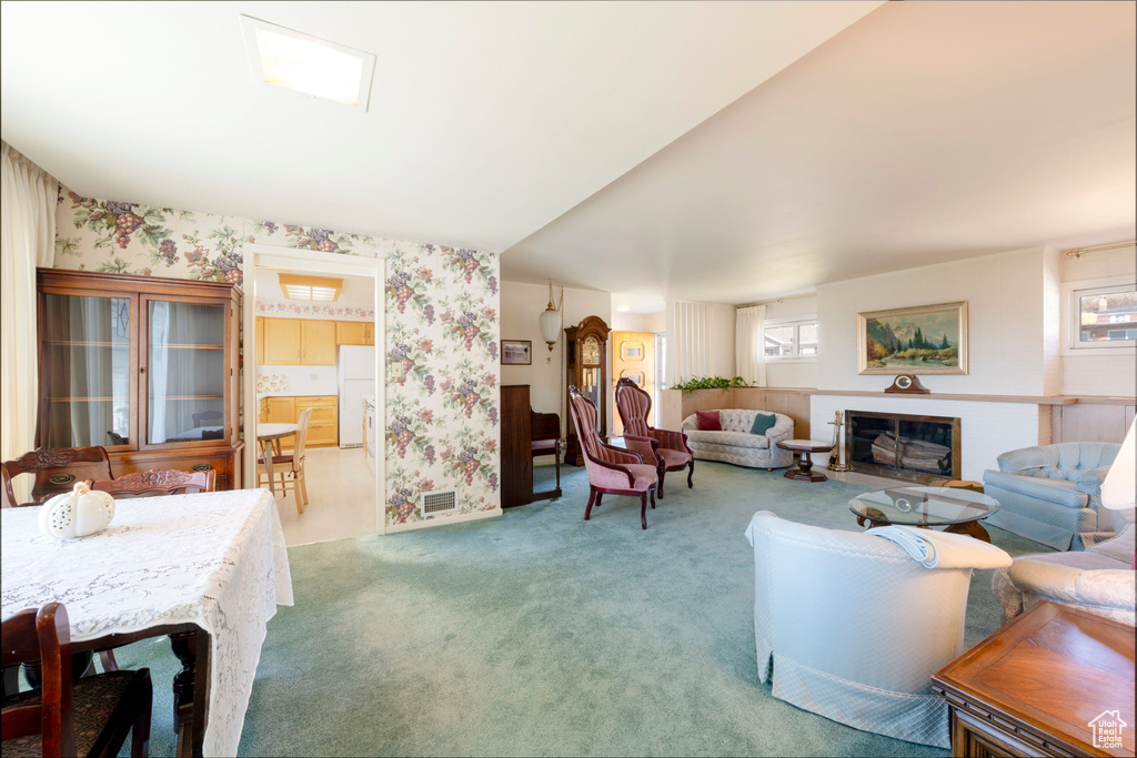 Carpeted living area featuring wallpapered walls, visible vents, and a fireplace