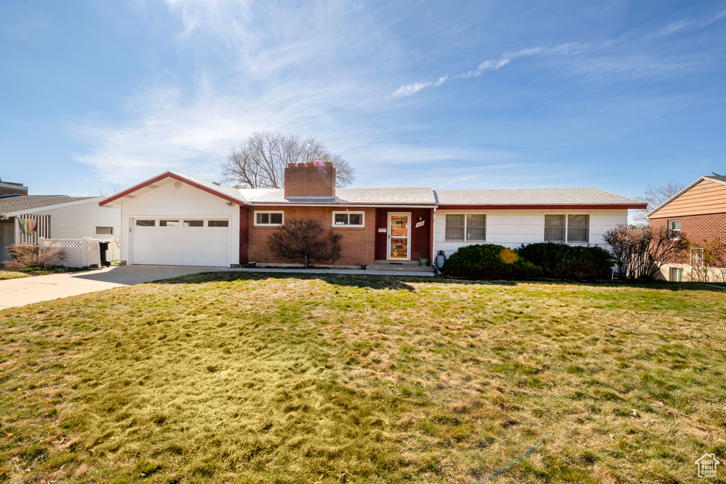 Ranch-style house featuring a front lawn, a chimney, a garage, and driveway