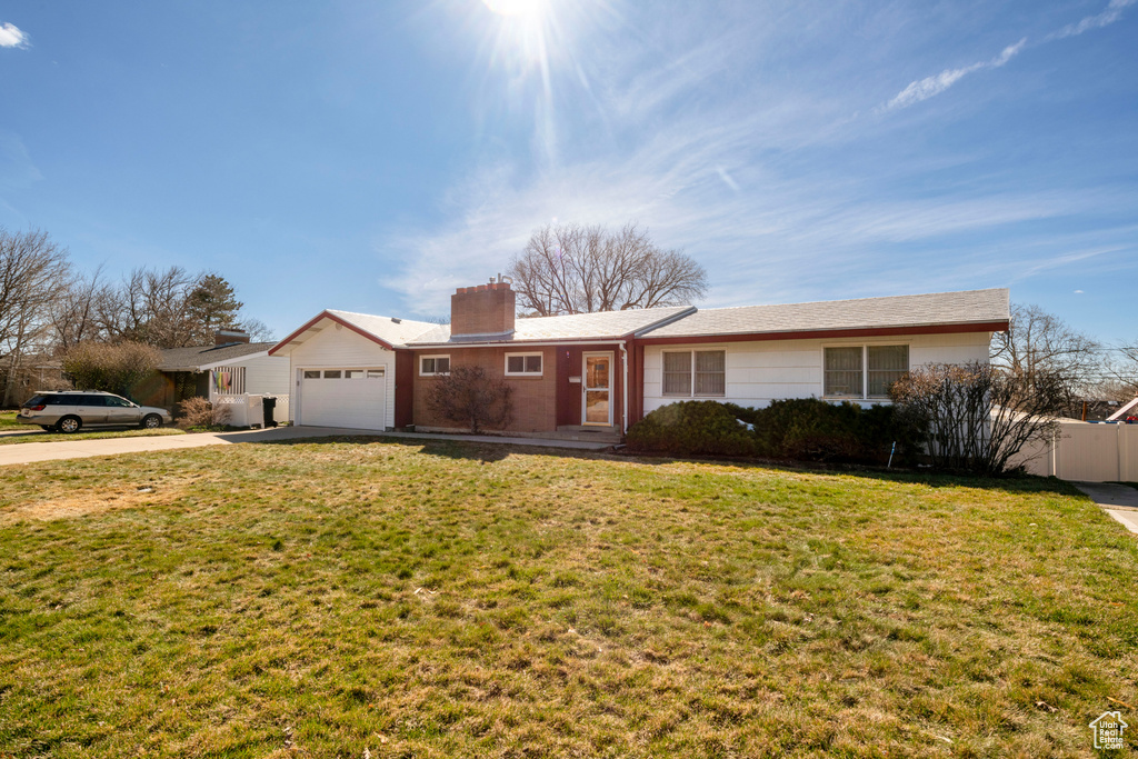 Ranch-style house with fence, a chimney, a garage, concrete driveway, and a front yard