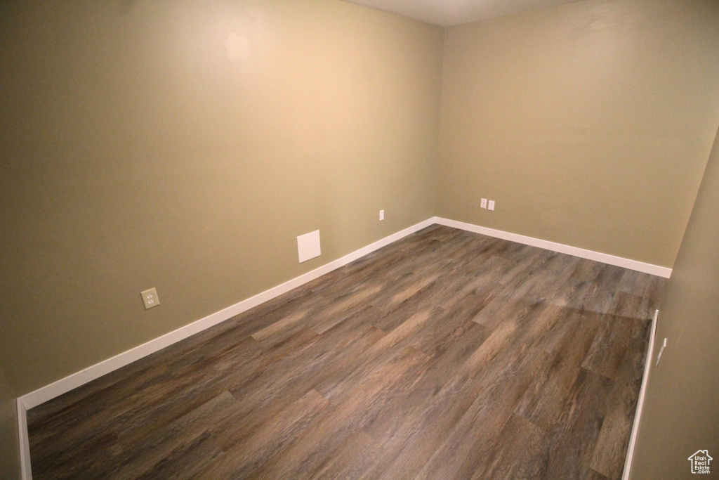Spare room featuring baseboards and dark wood finished floors