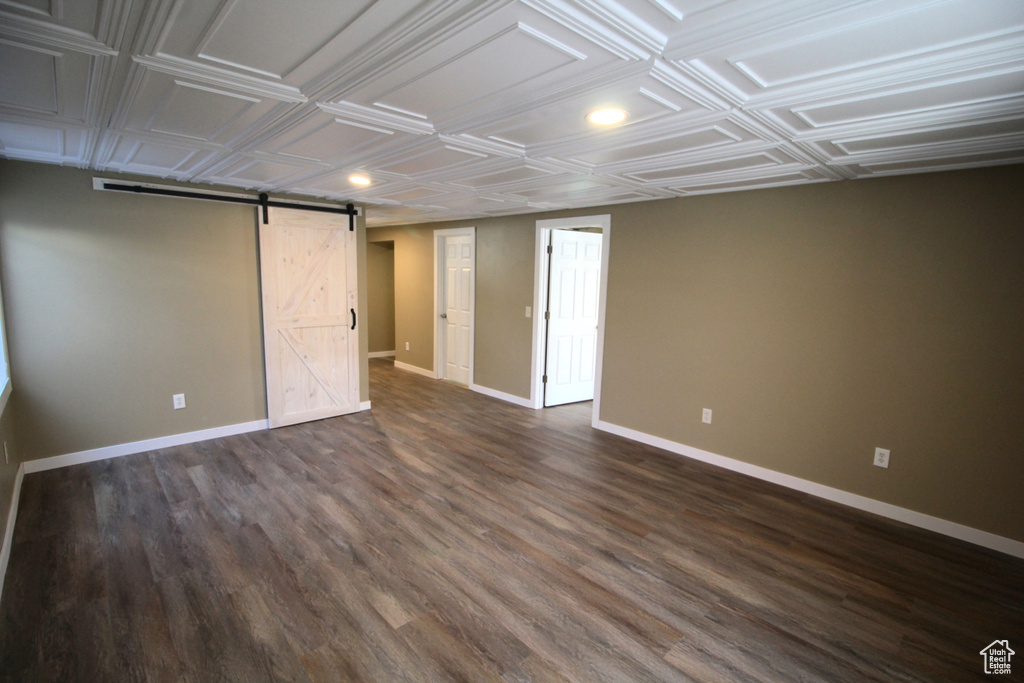 Interior space with recessed lighting, baseboards, a barn door, and dark wood-type flooring