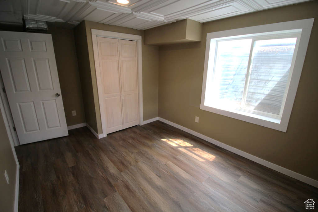 Unfurnished bedroom with baseboards, dark wood-style flooring, and a closet