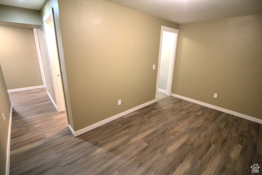 Spare room with baseboards and dark wood-type flooring