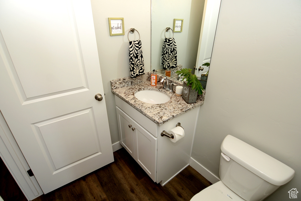 Bathroom with baseboards, wood finished floors, toilet, and vanity