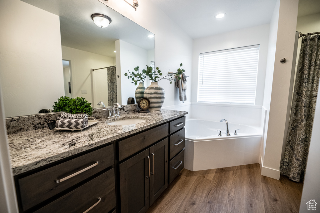 Bathroom with vanity, recessed lighting, a garden tub, curtained shower, and wood finished floors