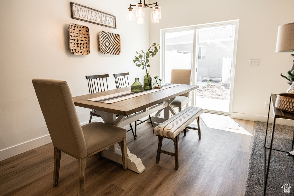 Dining area with baseboards, wood finished floors, a healthy amount of sunlight, and a notable chandelier