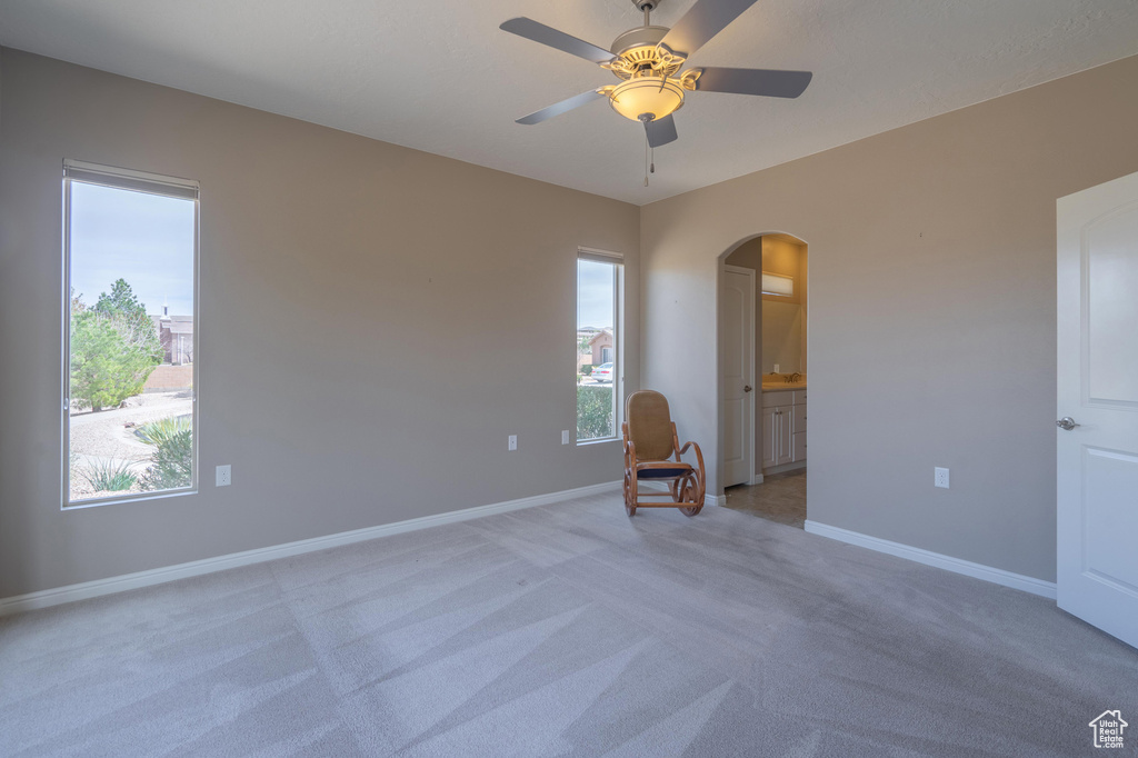 Unfurnished room with arched walkways, baseboards, a healthy amount of sunlight, and light colored carpet