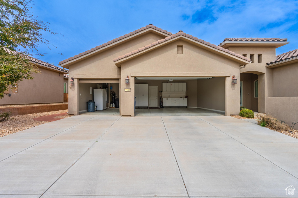 Mediterranean / spanish-style home featuring a tile roof, stucco siding, a garage, and concrete driveway