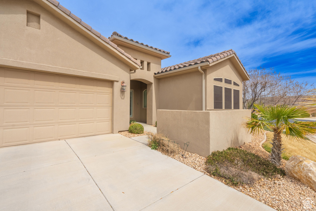 View of front facade with stucco siding, an attached garage, a tiled roof, and concrete driveway