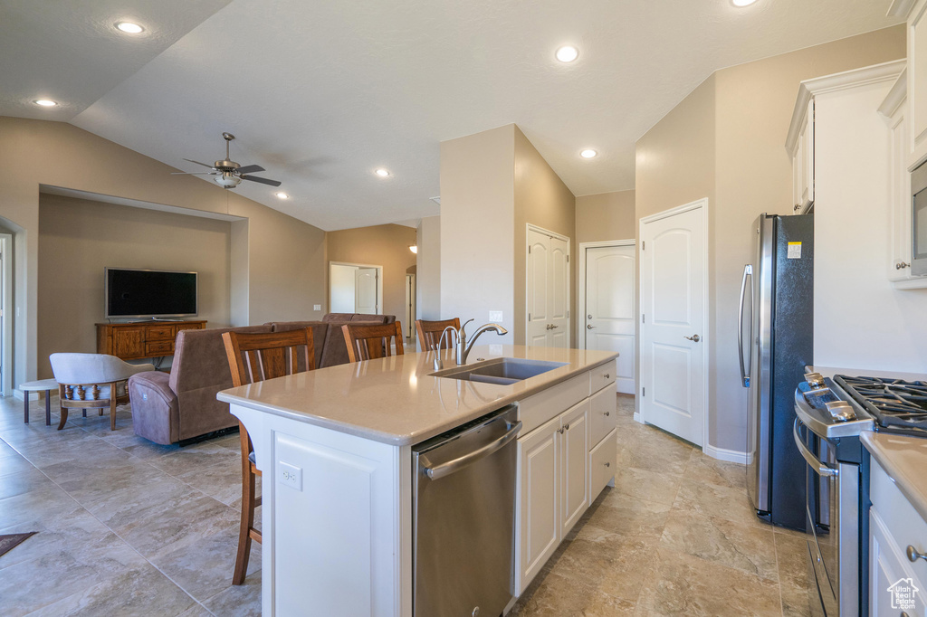 Kitchen with a ceiling fan, a breakfast bar area, a sink, white cabinets, and appliances with stainless steel finishes