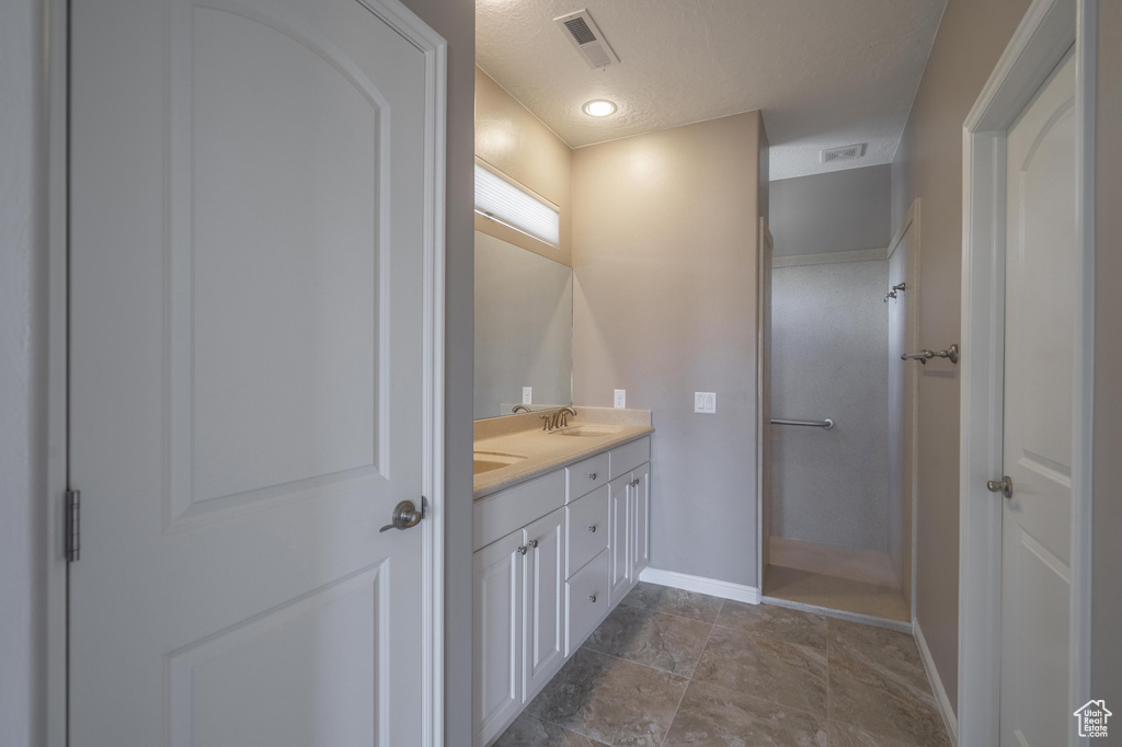 Bathroom featuring double vanity, a sink, baseboards, and visible vents