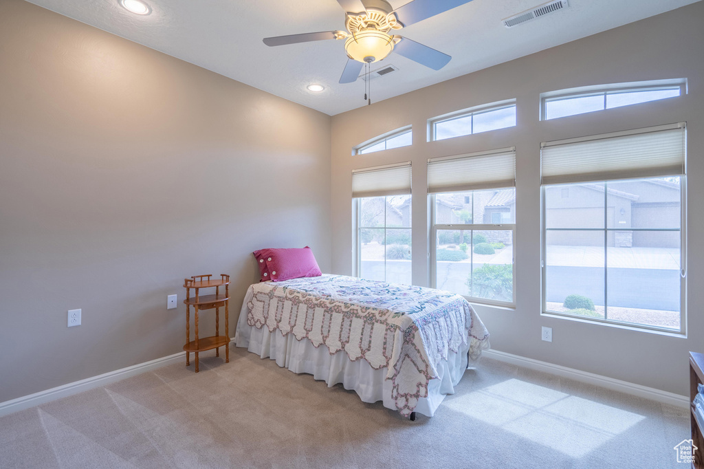 Bedroom with light carpet, multiple windows, visible vents, and baseboards
