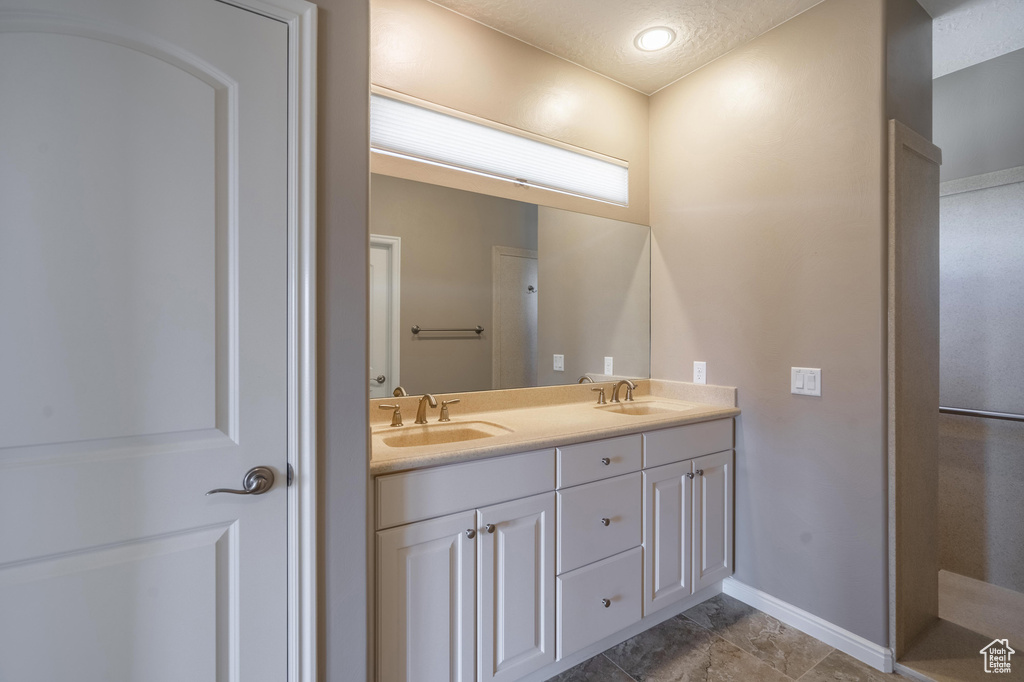 Full bath featuring double vanity, baseboards, and a sink