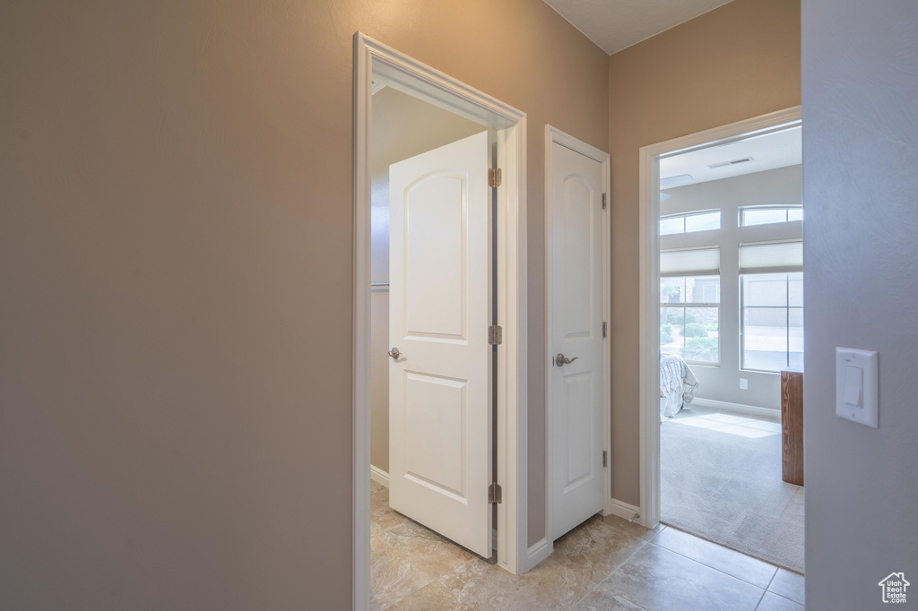 Corridor featuring baseboards and light colored carpet