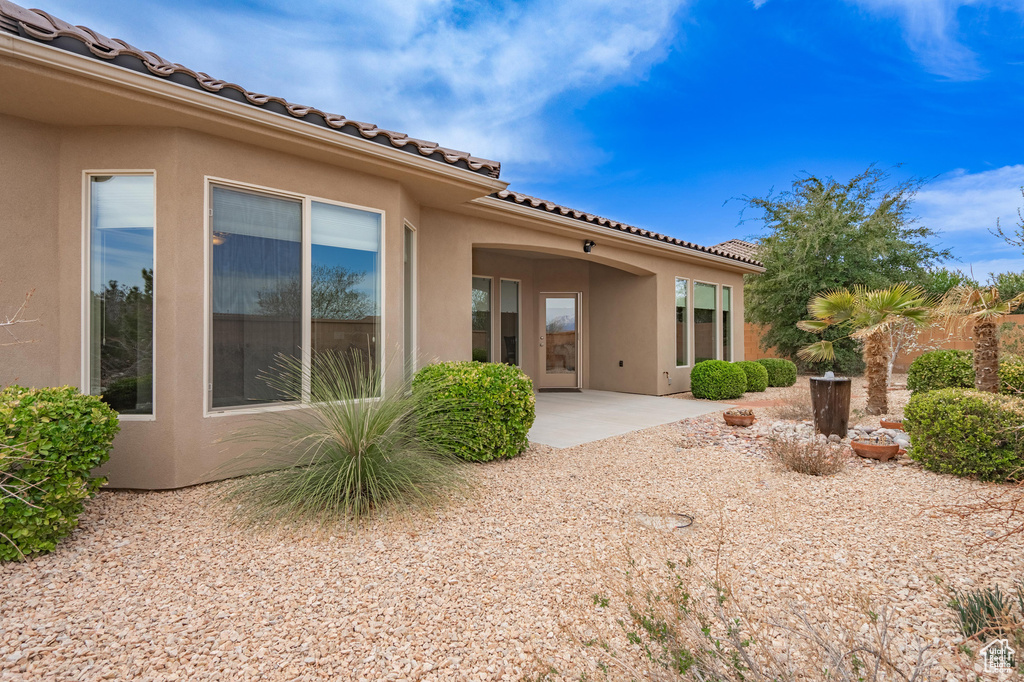 Back of property with a tile roof, stucco siding, and a patio area