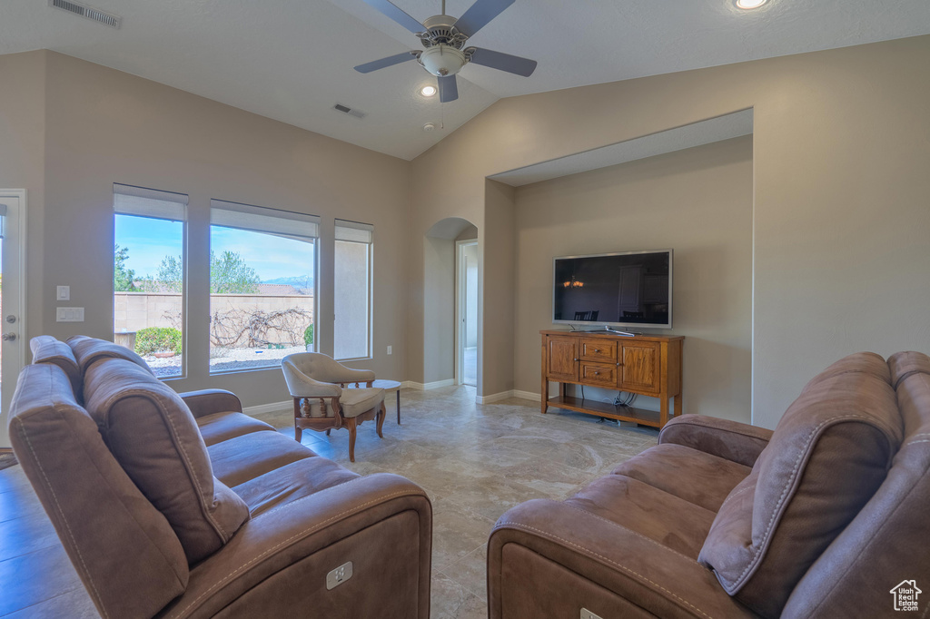 Living area with arched walkways, visible vents, vaulted ceiling, and a ceiling fan