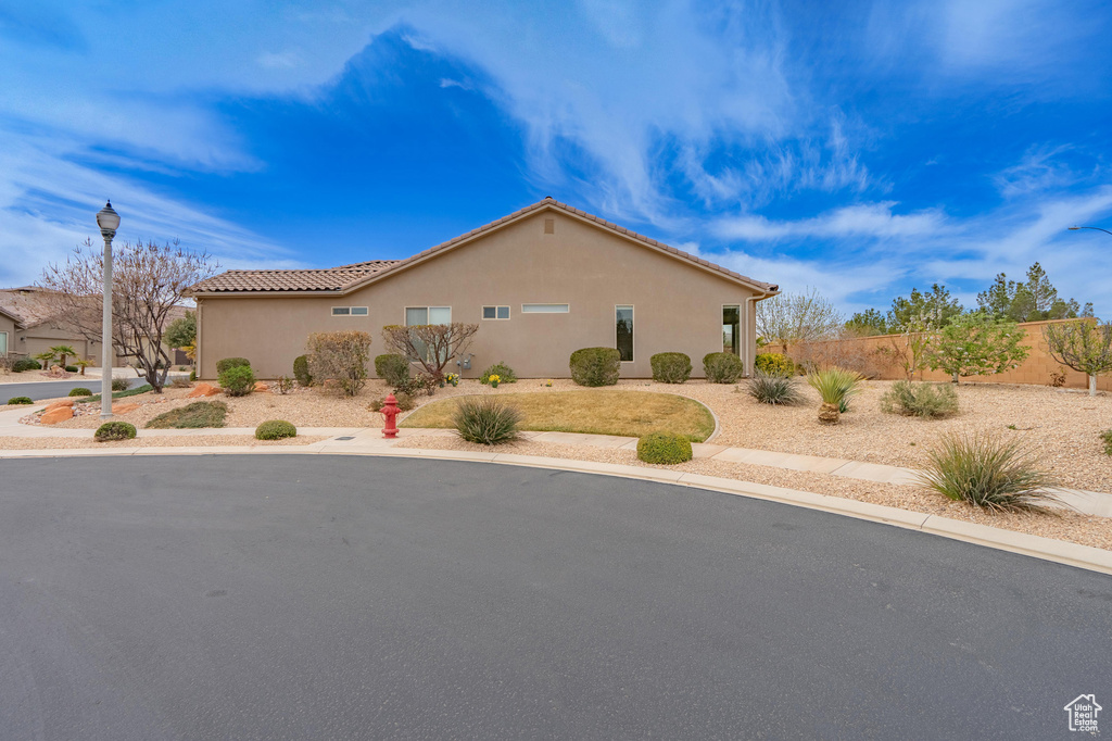 View of side of property featuring stucco siding, fence, and a tiled roof