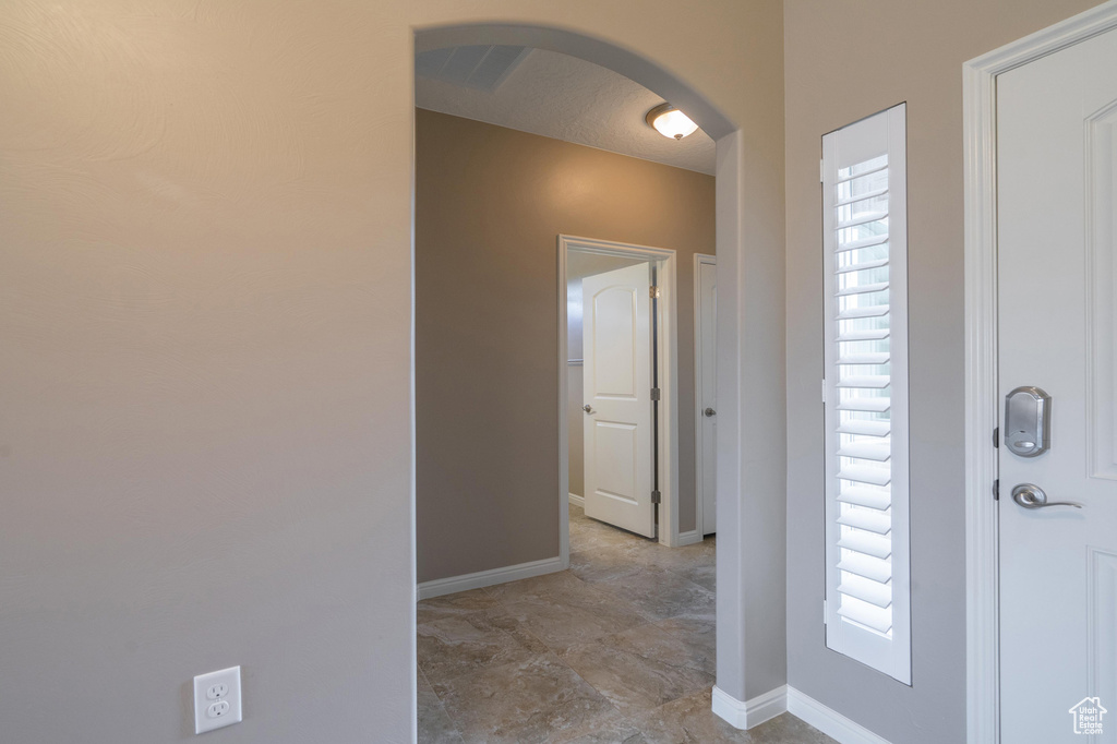 Entryway with arched walkways, baseboards, and a healthy amount of sunlight