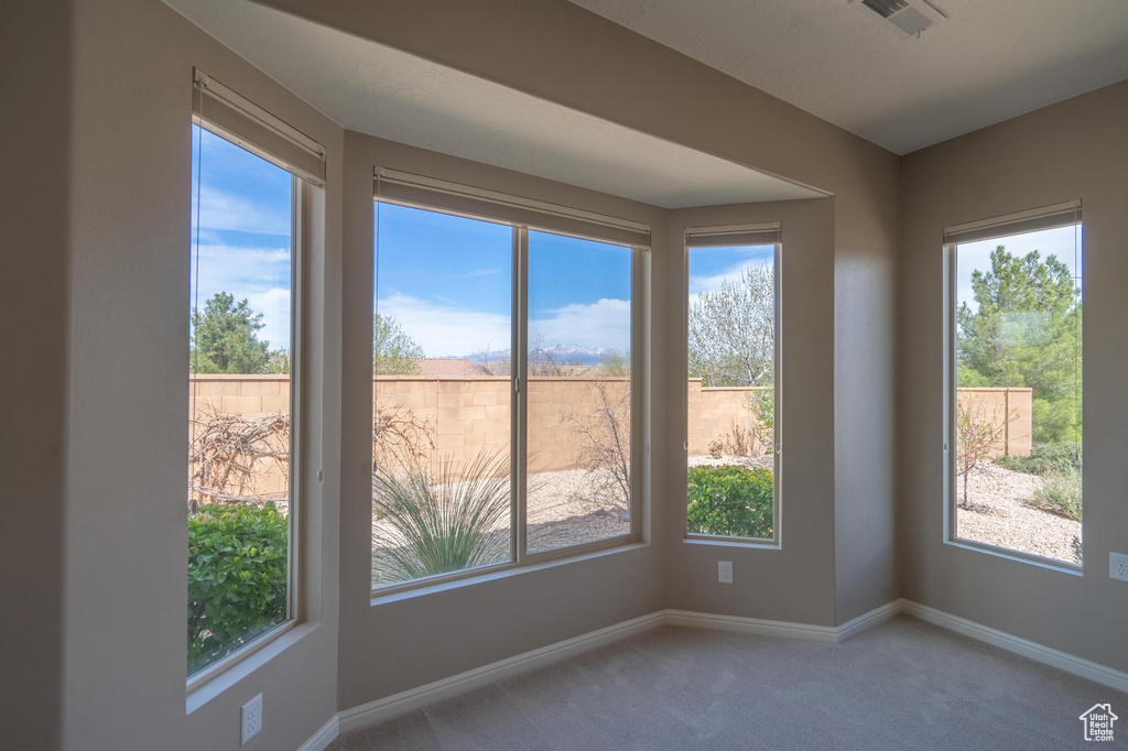 Empty room featuring carpet floors, plenty of natural light, baseboards, and visible vents