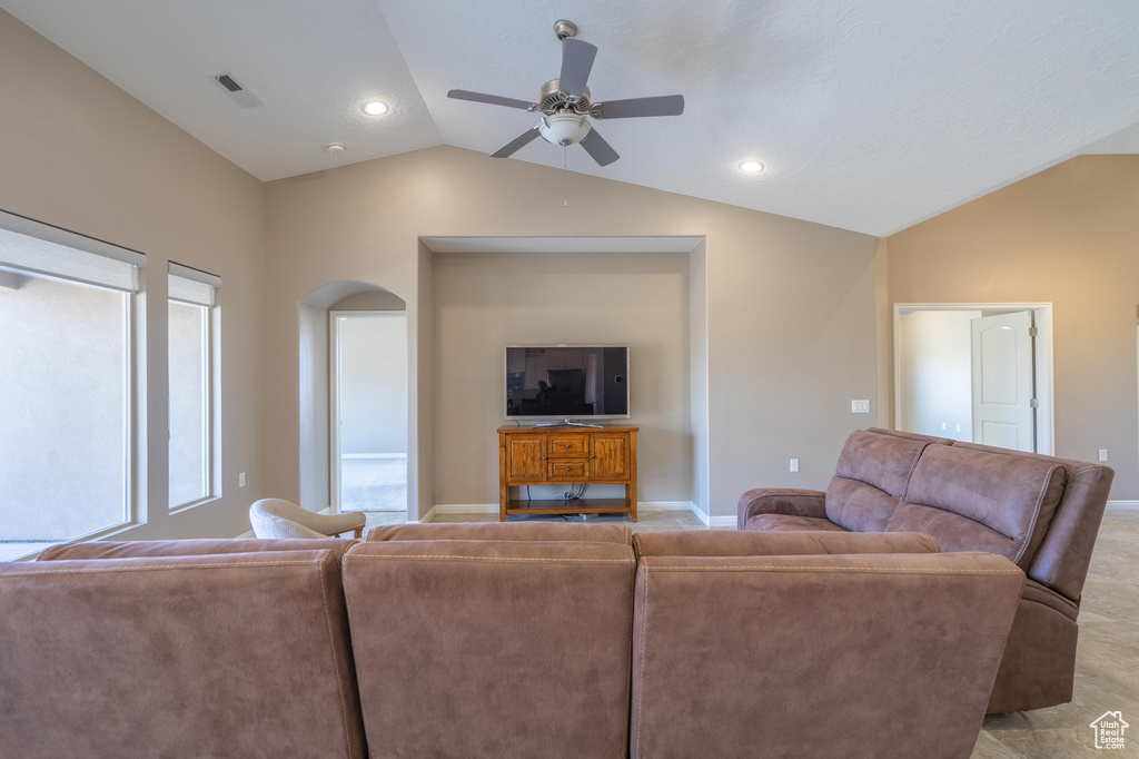 Living area featuring baseboards, vaulted ceiling, arched walkways, and a ceiling fan