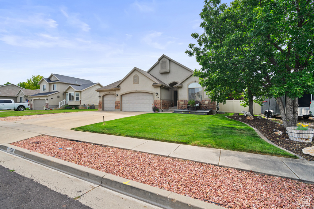 View of front facade featuring a garage, concrete driveway, a front lawn, stucco siding, and a residential view