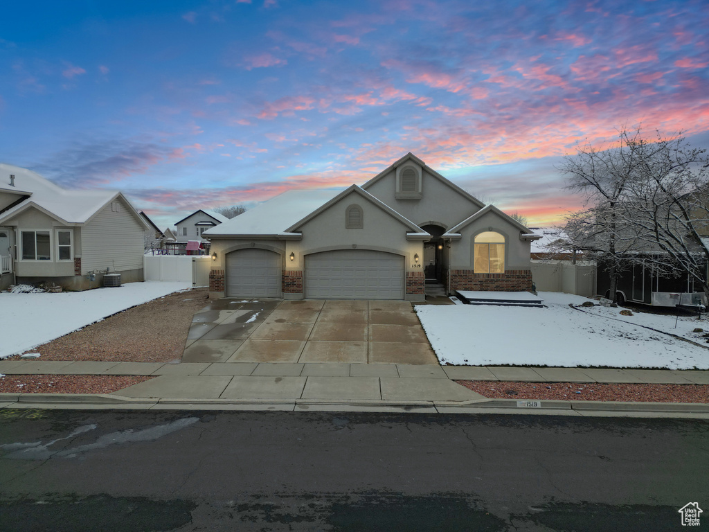 View of front of property featuring stucco siding, driveway, an attached garage, and fence