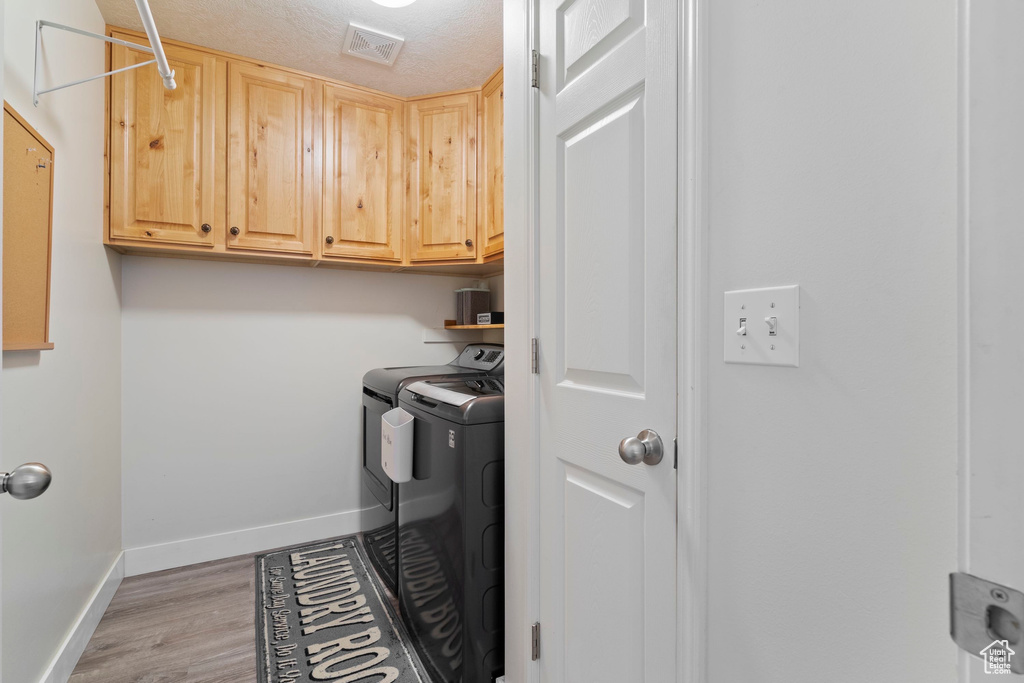Laundry room featuring visible vents, baseboards, light wood-style floors, cabinet space, and independent washer and dryer