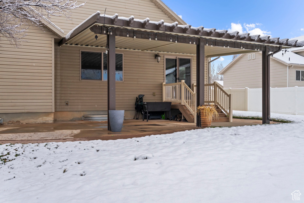 Snow covered rear of property featuring fence