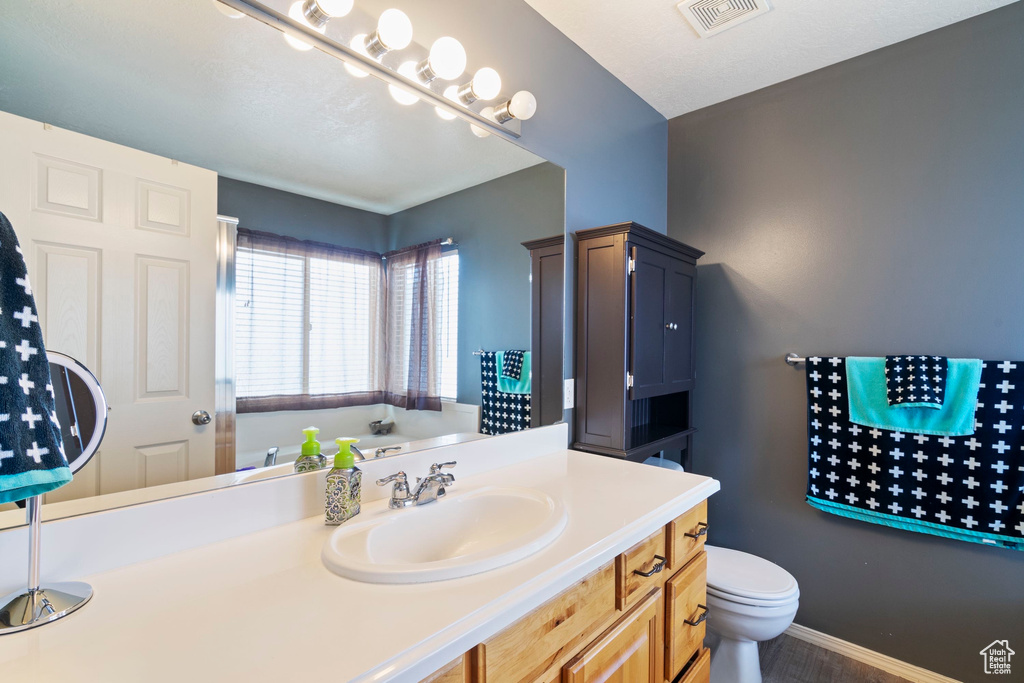 Bathroom featuring visible vents, baseboards, toilet, and vanity