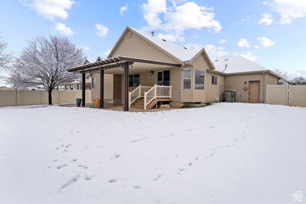 Snow covered property with a gate, fence, and a pergola