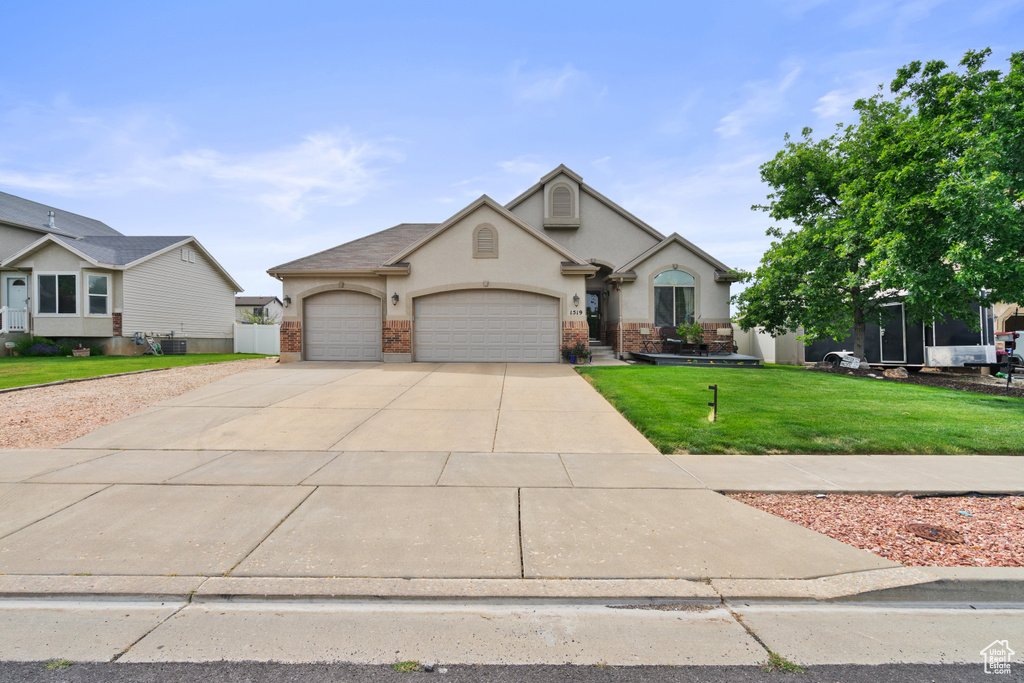 View of front of home with an attached garage, stucco siding, concrete driveway, and a front lawn