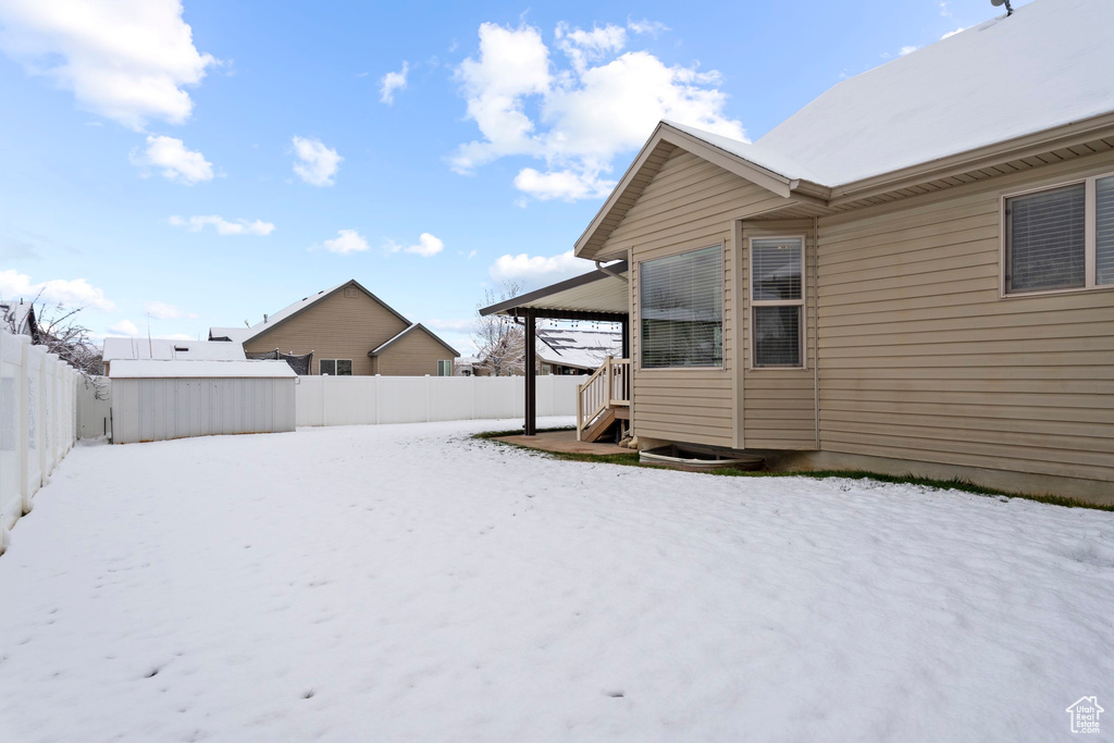 Yard covered in snow featuring an outdoor structure and a fenced backyard
