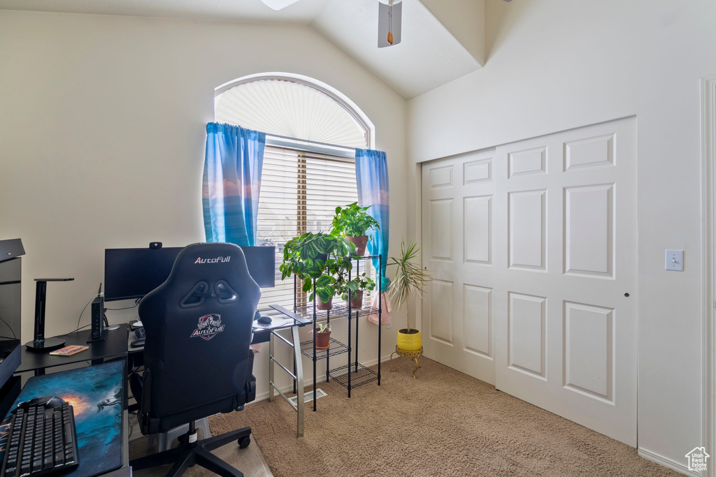 Home office featuring lofted ceiling, carpet, and ceiling fan