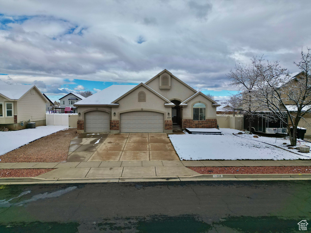 View of front of property with fence, a garage, driveway, and stucco siding
