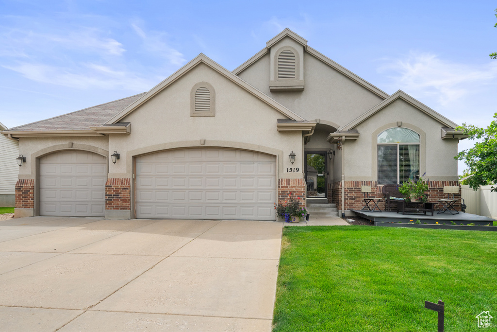 View of front of home featuring brick siding, concrete driveway, an attached garage, a front yard, and stucco siding