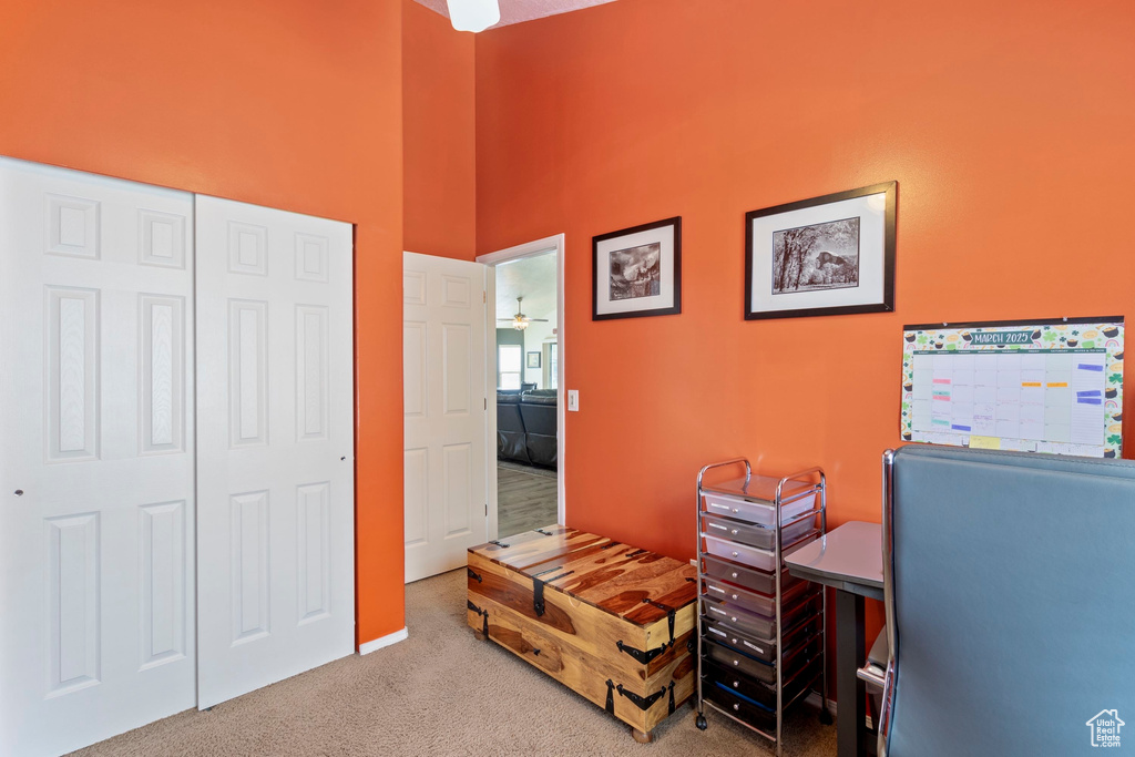 Interior space featuring a ceiling fan, a high ceiling, and carpet