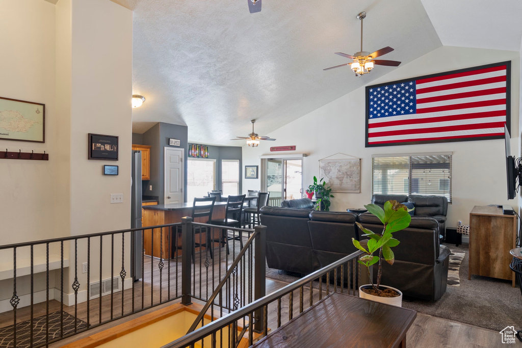 Interior space with wood finished floors, an upstairs landing, visible vents, and lofted ceiling