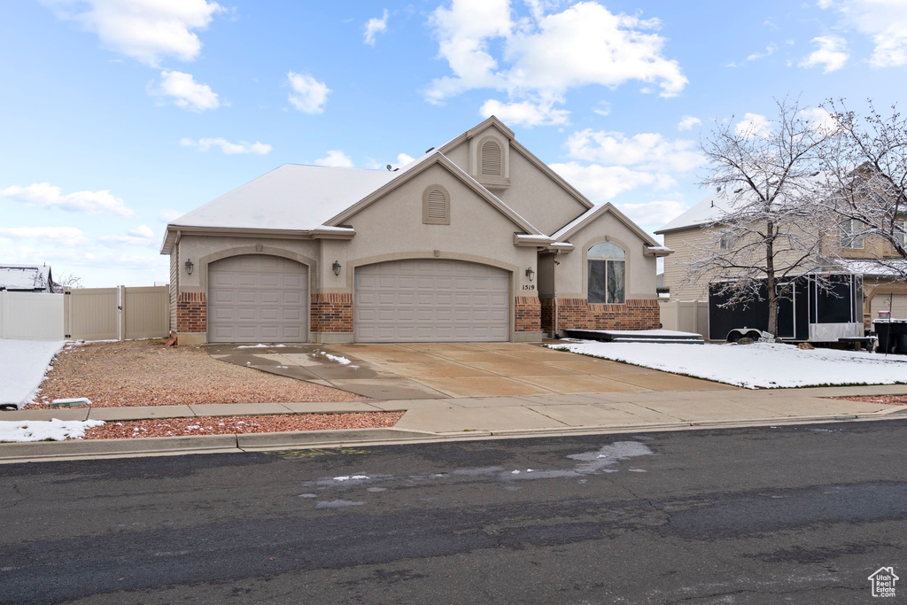 View of front of property featuring fence, concrete driveway, stucco siding, a garage, and a gate