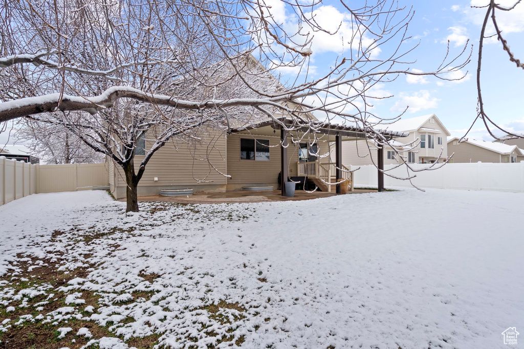 Snow covered back of property with fence
