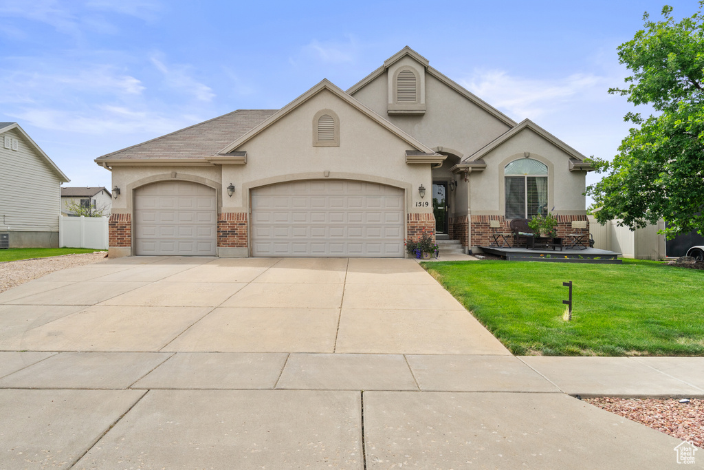 View of front of house with brick siding, a front lawn, an attached garage, and stucco siding