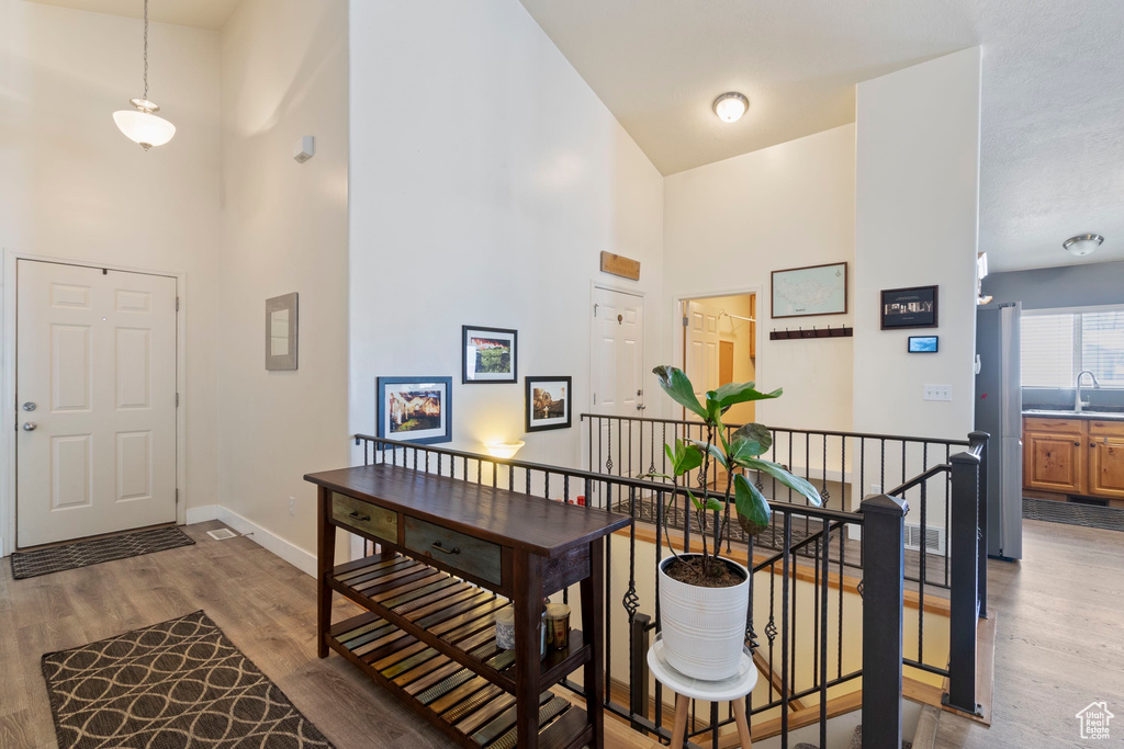 Foyer with baseboards, light wood-type flooring, and a high ceiling