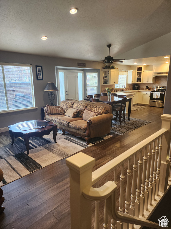 Living room with dark wood-style floors, recessed lighting, lofted ceiling, and a ceiling fan