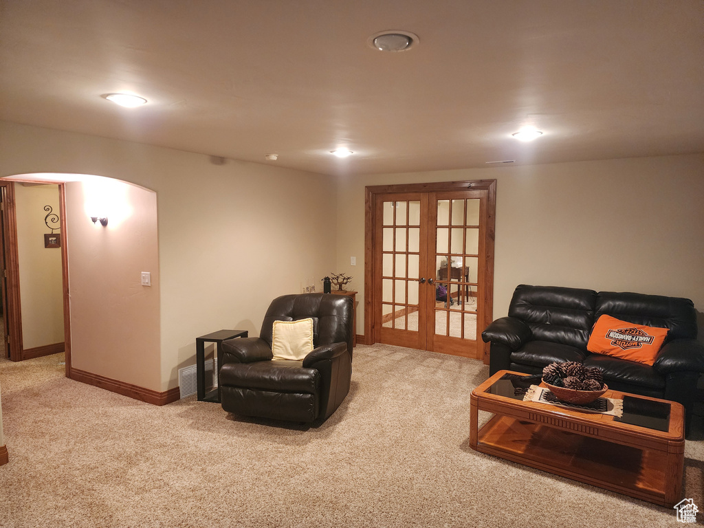Carpeted living room with arched walkways, french doors, and baseboards