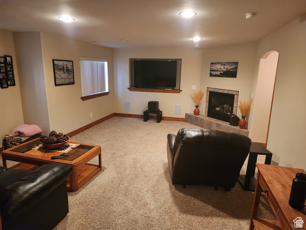 Carpeted living room with baseboards, arched walkways, and a tile fireplace