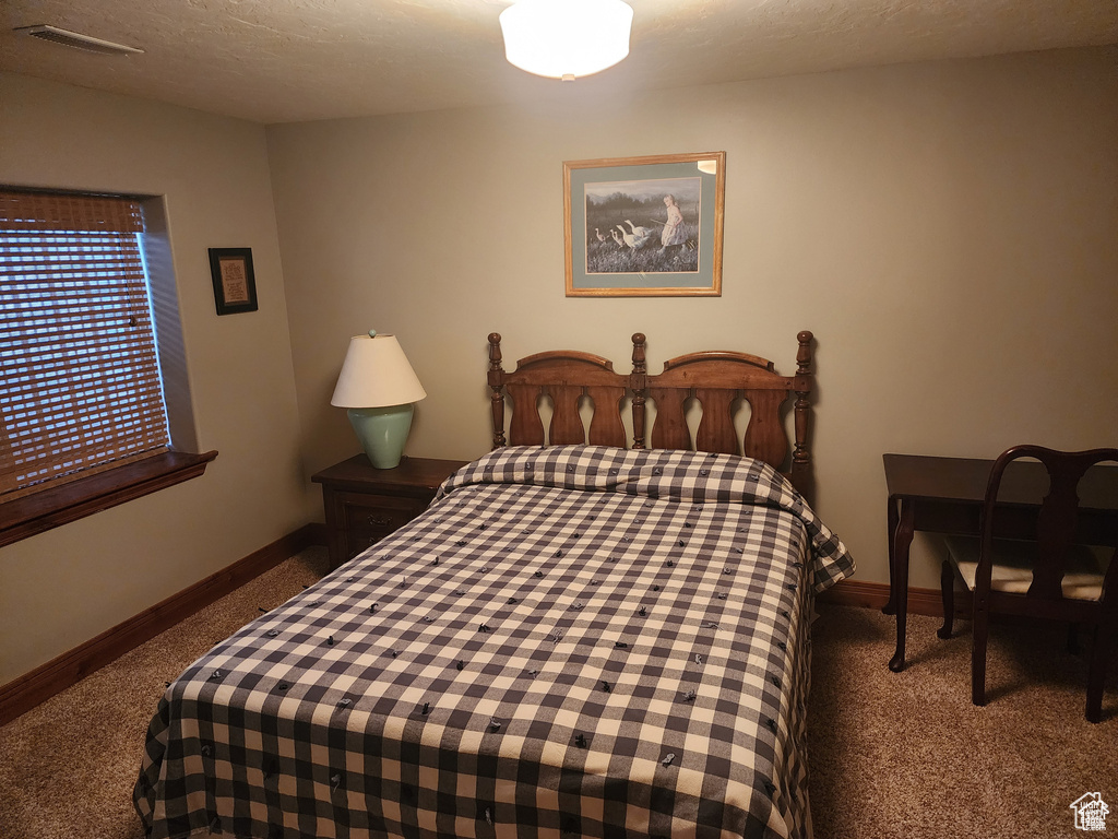 Carpeted bedroom with visible vents, a textured ceiling, and baseboards
