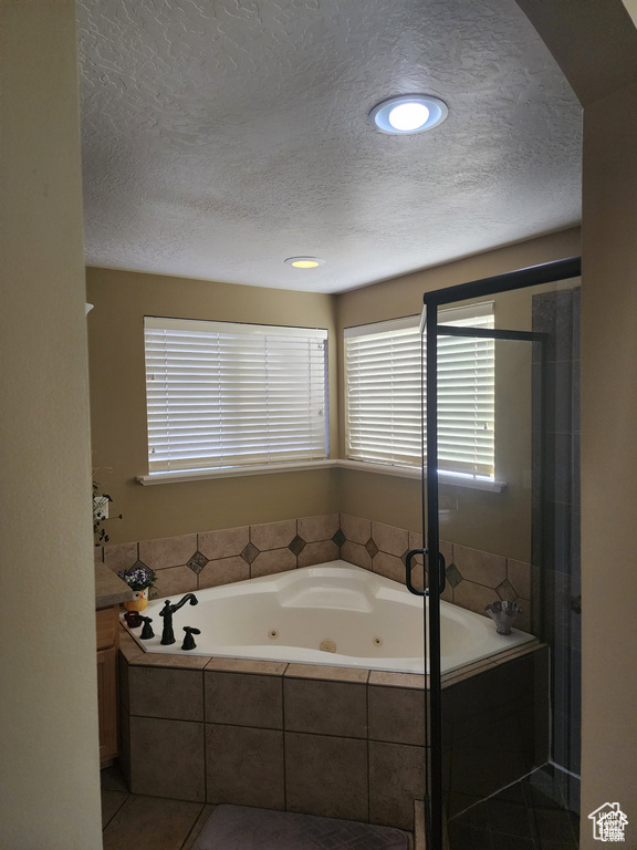 Bathroom with a shower stall, a textured ceiling, vanity, and a whirlpool tub